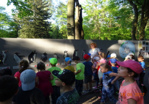 Dzieci oglądają namalowane na murze pingwiny.